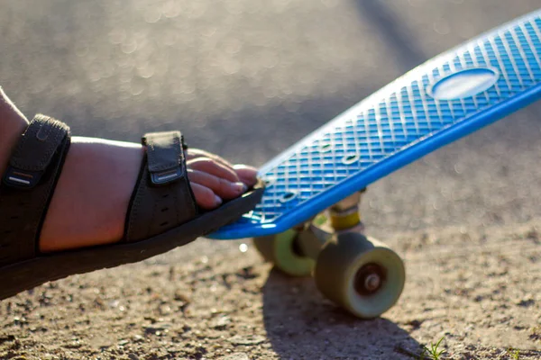 Defocus detailní záběr malý chlapec dělá triky na penny skateboard. Mladý kluk jezdí v parku na skateboardu. Dítě se naučí jezdit na modrém prkně a dělat kaskadérské kousky. Silnice. Rozostřeno — Stock fotografie