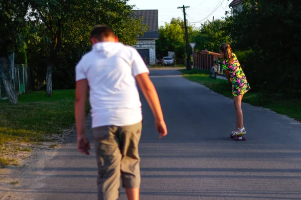 Defocus heureux jeune fille et garçon jouant sur le skateboard dans la rue. Elle a mis les bras sur les côtés des enfants caucasiens chevauchant un penny board, pratiquant le skateboard. Concept amusant d'amitié. Hors foyer — Photo