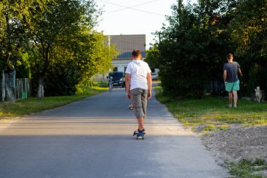 Defocus mutlu genç çocuk sokakta kaykay oynuyor. Arka planda köpeği olan bir adam. Kafkasyalı bir çocuk kaykay antrenmanı yapıyor. Çocukluk eğlence özgürlük konsepti. Odaklanamıyorum.