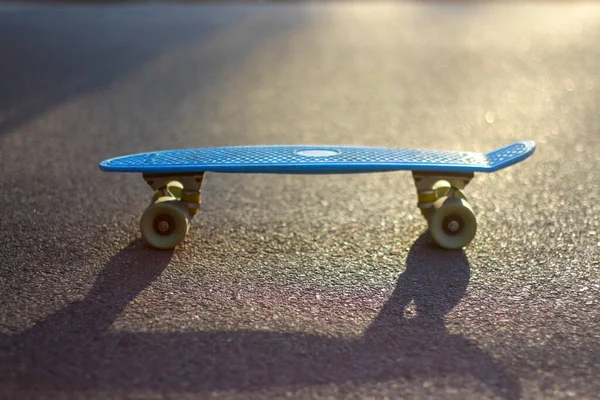 Defocus close-up blauw penny board op de asfaltweg in de zon buiten. Wazig bokeh. Mini kruiser. Sport concept. Skateboard staat in het midden. Begrepen, ruimte. Onscherp. — Stockfoto
