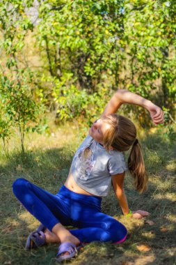 Defocus Kafkas ergen kız parkta, ormanda, dışarıda yoga yapıyor. Meditasyon, konsantrasyon. Sağlıklı bir yaşam tarzı. Yogacı kızın portresi. Dikey. Yeşil arka plan. Odaklanamıyorum.