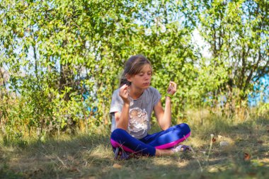 Defocus Kafkas ergen kız parkta, ormanda, dışarıda yoga yapıyor. Meditasyon ve konsantrasyon. Sağlıklı yaşam tarzı. Yogacı kız. Yeşil arka plan. Genel plan. Odaklanamıyorum