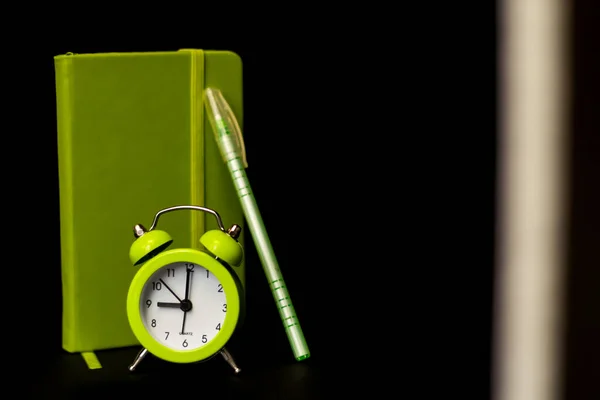 Светло Зеленый Будильник Ручкой Тетради Черном Темном Фоне Белой Полосой — стоковое фото