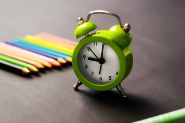 Siyah arka planda açık yeşil alarm saati. Okula dönelim. Zaman minimalist kavramı. Sabahın dokuzunda Seçici odak