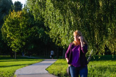 Defocus Kafkas sarışın kadın dışarıda, dışarıda telefonla konuşuyor. Mor bluzlu 40 'lı yaşlarda bir kadın parkta dikiliyor. Yetişkin kadınlar telefon kullanıyor. Uzayı kopyala Odaklanamıyorum.