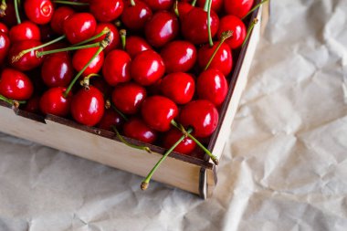Kırpılmış kağıt arka planda kuyruğu olan kırmızı kiraz çatalı. Yaz meyveleri ve meyveler. Hasat ve hasat konsepti. Organik yiyecekler. Üst Manzara. Çapraz. Yakın plan..