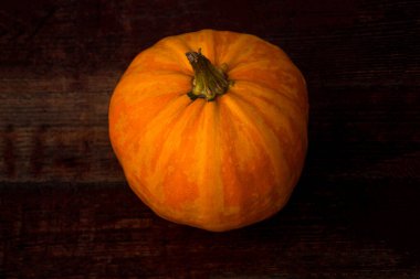 Koyu kiraz ağacından yapılmış parlak turuncu balkabağını kapat. Kusurlu balkabağı. Hasat konsepti. Seçici odak.