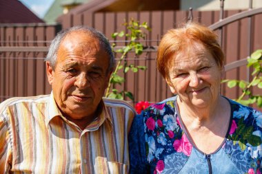 Yaz günü gülümseyen yaşlı bir çiftin portresi. Çiçek bahçesinde oturan mutlu yaşlı karı koca çifti. 60 'lar ya da 70' ler erkek ve kadın. Aşk ve aile kavramı.