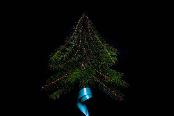 ターコイズリボンの雪のモミの枝で作られたクリスマスツリーの形 正方形の組成 フラットレイアウト 上からのビュー 冬のトウヒの概念 黒の背景 選択的焦点 — ストック写真