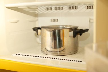 a frozen freezer or refrigerator compartment with thick layers of ice, using a saucepan of boiling water inside to melt the frost.
