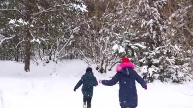 Defocus çocuğu bir kızla kartopu heykeli yapıyor. Kış Parkı 'nda kar topu oynayan komik çocuklar, açık havada vakit geçiriyorlar. Karlı, karlı, ormanlık, soğuk, dondurucu bir hava. Ergenlik. Arkadan bak. Odaklanamıyorum.