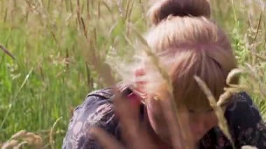 Yüksek otlu bir tarlada oturan, çilek toplayan, böğürtlen arayan defocus kadını. Çilek kokusunun tadını çıkar. Yaz yemeği. Zenginlik ve doğaya yakınlık Odaklanamaz.