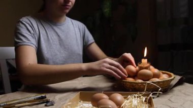 Ateşin yanında yumurtayı tutan, ısıtan ve boyayan genç bir kadın. Folk tasarımlarıyla süslenmiş Ukrayna Paskalya yumurtalarını boyamaya hazırlanıyorlar. Pysanka, Paskalya yumurtası. Gece.