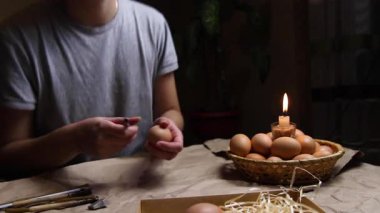 Ateşin yanında yumurtayı tutan, ısıtan ve boyayan genç bir kadın. Folk tasarımlarıyla süslenmiş Ukrayna Paskalya yumurtalarını boyamaya hazırlanıyorlar. Pysanka, Paskalya yumurtası.