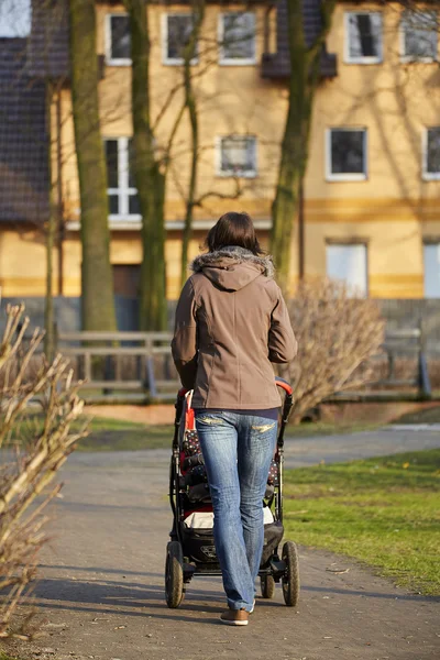 Kvinna med barnvagn i höstlig park — Stockfoto