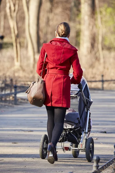 Kvinna med barnvagn i höstlig park — Stockfoto