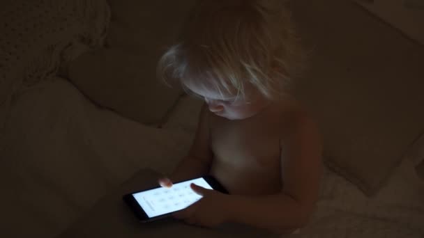 Ένα πορτρέτο του ένα χαριτωμένο μωρό έλεγχο smartphone που βρίσκεται σε ένα κρεβάτι — Αρχείο Βίντεο