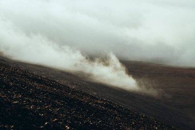 Bulutların arasındaki dağlık vadiden dağlık araziye bak. Atmosferik karanlık minimalist dağ manzarası alçak bulutlar dağ vadisinde. Yerde kalın bulutlar olan harika dağ manzarası