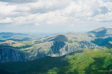 Gökyüzü manzaralı yeşil dağlara bakıyor. Dev yeşil dağlardaki bulutların gölgeleri. Atmosferik dağlık arazi ve uzun vadi. Dağlık bölgede sakin bir atmosfer. Yüksek irtifada görkemli manzara.
