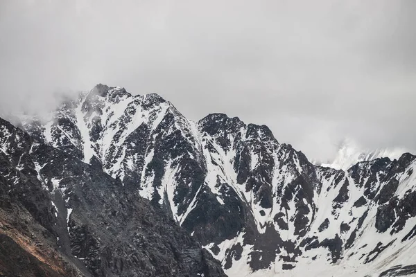 在多云的天空下 大气极简主义高山景观 巨大的冰河悬挂在高山的最高峰上 白雪覆盖的广阔山脉上空的低云 高空雾蒙蒙的壮丽风景 — 图库照片
