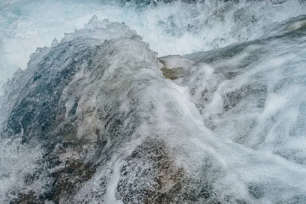 Full frame nature background of water riffle of mountain river. Powerful water stream of mountain creek with rapids. Natural textured backdrop of fast flow of mountain brook. Rapids texture close-up.