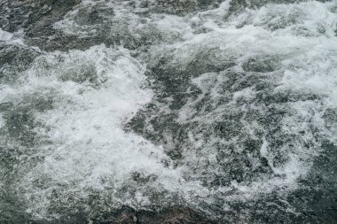 Dağ nehrinin su tabancasının tam çerçeveli arka planı. Akıntılı dağ deresinin güçlü su akıntısı. Dağ deresinin doğal desenli akışı. Hızlı desen yakın plan.
