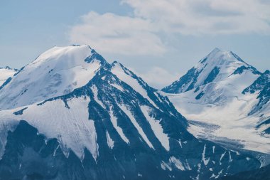 Atmosferik minimalist alp manzarası karlı dağ zirvesinde asılı devasa bir buzulla. Buzul sınırında büyük bir balkon. Karlı dağların üzerindeki bulutlu gökyüzü. Yüksek irtifada görkemli manzara.