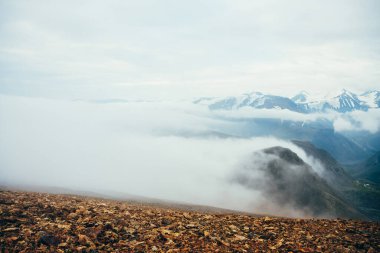 Atmosferik dağlık araziden kayalık dağların tepesindeki dev alçak bulutlara. Highland Vadisi 'nin üzerinde büyük, kalın bulutlar. Yüksek irtifada harika bir manzara. Buzullu, karlı dağ sırasının yamacından manzarayı izle.