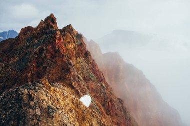 Bulutlu gökyüzünde güzel, sivri, kayalık bir zirve. Canlı, sivri, kayalık bir tepe. Dev bir taş parçası. Atmosferik minimalist alp manzarası. Gökyüzünde keskin kayalık bir dağ tepesi. Muhteşem dağlık manzara.