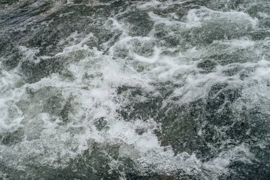 Dağ nehrinin su tabancasının tam çerçeveli arka planı. Akıntılı dağ deresinin güçlü su akıntısı. Dağ deresinin doğal desenli akışı. Hızlı desen yakın plan.