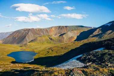 Güzel dağ gölü ve güneş ışığında karla kaplı sıradağların harika manzarası. Parlak mavi gölü olan ve güneşli bir günde kayalara vuran muhteşem bir dağ manzarası. Renkli karşıtlık yükseklik manzarası.