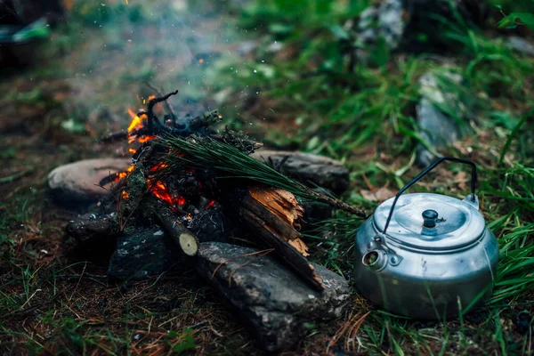 Kamp ısıtıcısı kamp ateşinin yanında. Vahşi doğada rahat bir kamp yeri. Kamp ateşinin harika akşam atmosferik arka planı. Küçük sihirli şenlik ateşinin güzel alevi. Ateşli romantik sıcak bir yer.