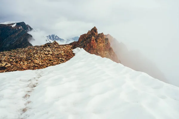 Μυτερή Βραχώδης Κορυφή Στο Βουνό Χιόνι Ανάμεσα Πυκνά Χαμηλά Σύννεφα — Φωτογραφία Αρχείου