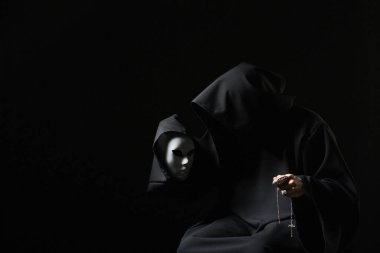 Siyah mantolu kötü büyücü ve kollu bir şeytan. Şeytanla ayinsel anlaşma. Kişiliği bölünmüş bir adam. Şizo maskeyle konuşuyor. Lanetli suikastçı kötü ruhu karanlık odada bitirir. Keşiş laneti. Kötü büyücü..