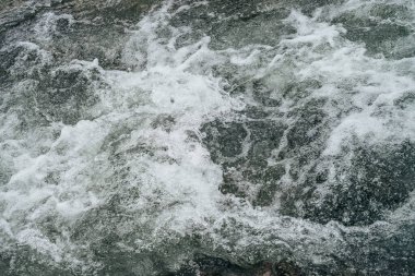 Dağ nehrinin su tabancasının tam çerçeveli arka planı. Akıntılı dağ deresinin güçlü su akıntısı. Dağ deresinin doğal desenli akışı. Hızlı desen yakın plan.