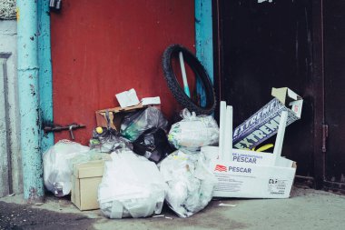 Şehir binasının girişine çöp yığılmış. Çöp yığını çöp kanalını tıkadı. Atılmış bir sürü şey yanlış yerde. Çöp atma kurallarının ihlali. Rusya, Barnaul, 10 Haziran 2019.