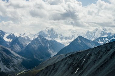 Gri bulutlu gökyüzünün altında kocaman buzul dağları olan muhteşem dramatik alp manzarası. Karlı dağlara ve buzullara harika bir dağ manzarası. Büyük kayalar ve buzullarla atmosfer manzarası.