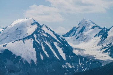 Atmosferik minimalist alp manzarası karlı dağ zirvesinde asılı devasa bir buzulla. Buzul sınırında büyük bir balkon. Karlı dağların üzerindeki bulutlu gökyüzü. Yüksek irtifada görkemli manzara.