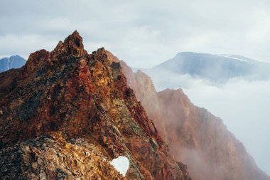 Bulutlu gökyüzünde güzel, sivri, kayalık bir zirve. Canlı, sivri, kayalık bir tepe. Dev bir taş parçası. Atmosferik minimalist alp manzarası. Gökyüzünde keskin kayalık bir dağ tepesi. Muhteşem dağlık manzara.
