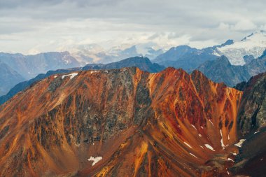 Atmosferik alp manzarası ve altın saatinde kırmızı kayalar. Büyük portakal kayaları ve gün doğumunda buzullu dev karlı dağların manzarası. Harika bir dağ manzarası. Dağların üzerinden uçarken.
