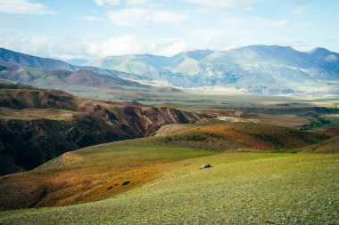 Derin vadisiyle muhteşem canlı bir dağ manzarası. Çok renkli dağlar, yeşil geçitler ve gün ışığında vadi. Güzel tepeleri ve kayaları olan güneşli bir manzara. Alışılmadık rahatlamaya renkli görünüm.