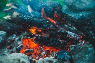 Yanan odun odunları yakın plan ateşte yanmış. Atmosferik arka plan ve turuncu kamp ateşi. Bokeh 'te kıvılcımlar saçan şenlik ateşinin tam kare görüntüsü. Parlayan közlerin sıcak girdabı ve havadaki küller
