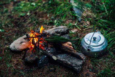 Kamp ısıtıcısı kamp ateşinin yanında. Vahşi doğada rahat bir kamp yeri. Kamp ateşinin harika akşam atmosferik arka planı. Küçük sihirli şenlik ateşinin güzel alevi. Ateşli romantik sıcak bir yer.