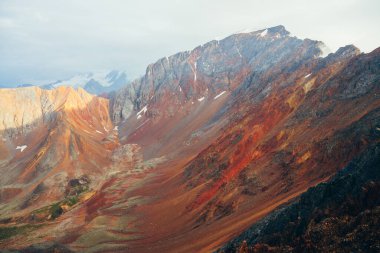 Büyük kayalık dağ sırtına çok renkli canlı bir manzara. Devasa dağlık sert duvar, yakın plan. Kırmızı turuncu sarı taşlar ve taşlar. Renkli kayaların güzel manzarası. Çok renkli dağ sırası..