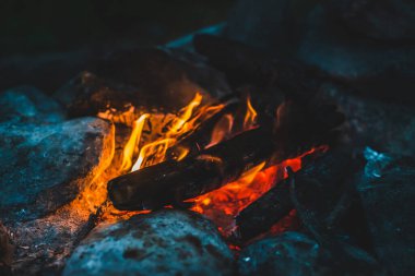 Yanan odun odunları yakın plan ateşte yanmış. Atmosferik sıcak arka plan ve turuncu kamp ateşi. Şenlik ateşinin hayal edilemez tam kare görüntüsü. Güzel ateşte odun yakmak. Harika alev.