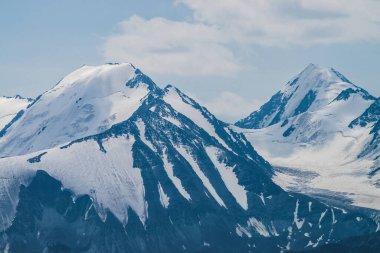 Atmosferik minimalist alp manzarası karlı dağ zirvesinde asılı devasa bir buzulla. Buzul sınırında büyük bir balkon. Karlı dağların üzerindeki bulutlu gökyüzü. Yüksek irtifada görkemli manzara.