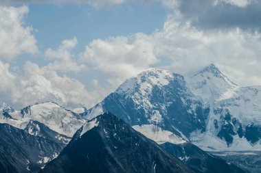 Hava bulutluyken, çok güzel buzul dağları olan muhteşem bir manzara. Bulutlu gökyüzünün altında buzulları olan harika karlı dağ. Kasvetli bulutlu atmosferik manzara Büyük kayalar ve buzullarla.