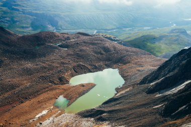 Asit yeşili rengin en güzel buzul gölü. Zümrüt dağ gölü ve Highland Vadisi 'ndeki küçük nehir. Kayaların ve taşların arasında su üzerindeki buz parçaları. Sıradışı yeşil tonlardan oluşan muhteşem alp gölü.