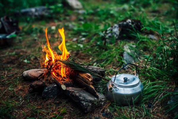 Camping kettle near small camp fire close-up. Cozy camping place in wild. Wonderful evening atmospheric background of campfire. Beautiful flame of small magic bonfire. Romantic warm place with fire.