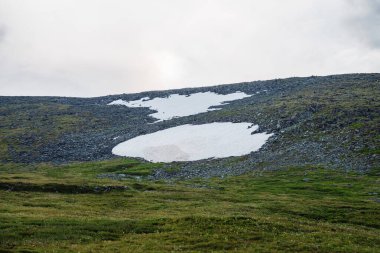 Dağ geçidinde kar tarlası olan minimalist dağlık arazi. Dağ yamacında karlı minimum alp manzarası. Karlı tepe. Karlı yamaca atmosferik görüş. Yüksek irtifada görkemli doğa.